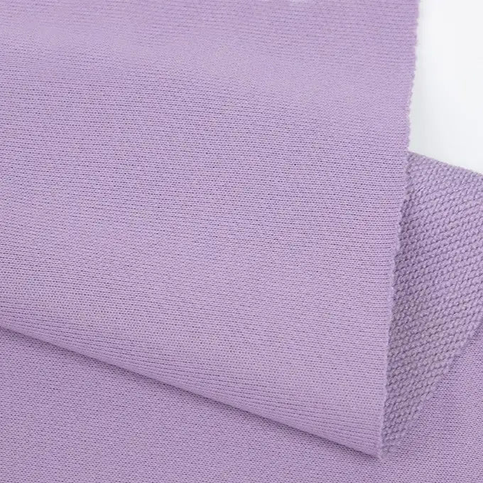 A close-up of two overlapping pieces of Longan Craft Plain Color French Terry Fabric in light purple, showcasing the soft, smooth polyester texture and visible weave—ideal for winter clothing.