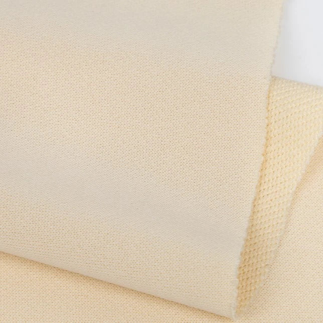 Longan Craft’s Plain Color French Terry Fabric By The Yard features soft, lightweight polyester with a smooth front and a slightly textured reverse—ideal for winter clothing. The fabric is shown in beige, folded to display its fine weave.