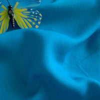 A close-up of Longan Craft's Plain Color Jersey Viscose Fabric shows gentle folds and a blue and yellow butterfly in the upper left corner; this 100% rayon viscose material is perfect for dresses and available by the yard.