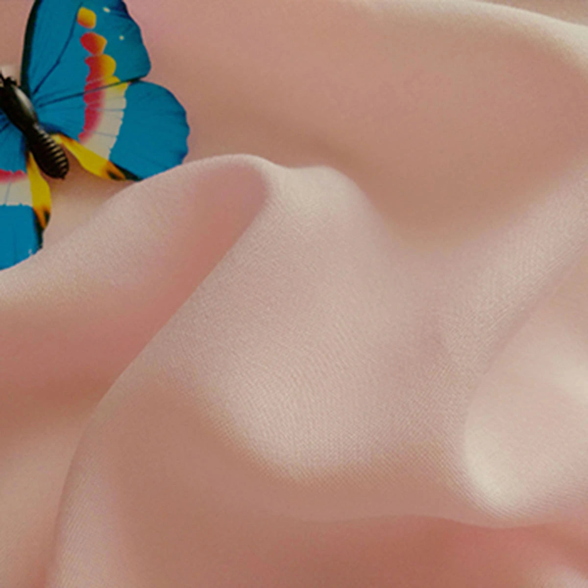 A vibrant blue butterfly with yellow, pink, and black markings rests on Longan Craft Plain Color Jersey Viscose Fabric by the Yard—100% rayon, soft and perfect for dresses.