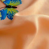 A blue and yellow butterfly rests on Longan Craft's Plain Color Jersey Viscose Fabric by the yard, a soft 100% rayon material with gentle folds and smooth texture—perfect for dresses.