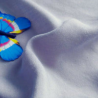 A blue and yellow decorative butterfly rests on soft, wavy folds of Longan Craft’s Plain Color Jersey Viscose Fabric By The Yard, a 100% rayon viscose material perfect for dresses.