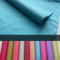 A roll of Longan Craft's Plain Color Taffeta Silk Fabric By The Yard lies unrolled in light blue, with neatly arranged high-quality bridal mulberry silks below in pink, red, green, beige, teal, and purple.