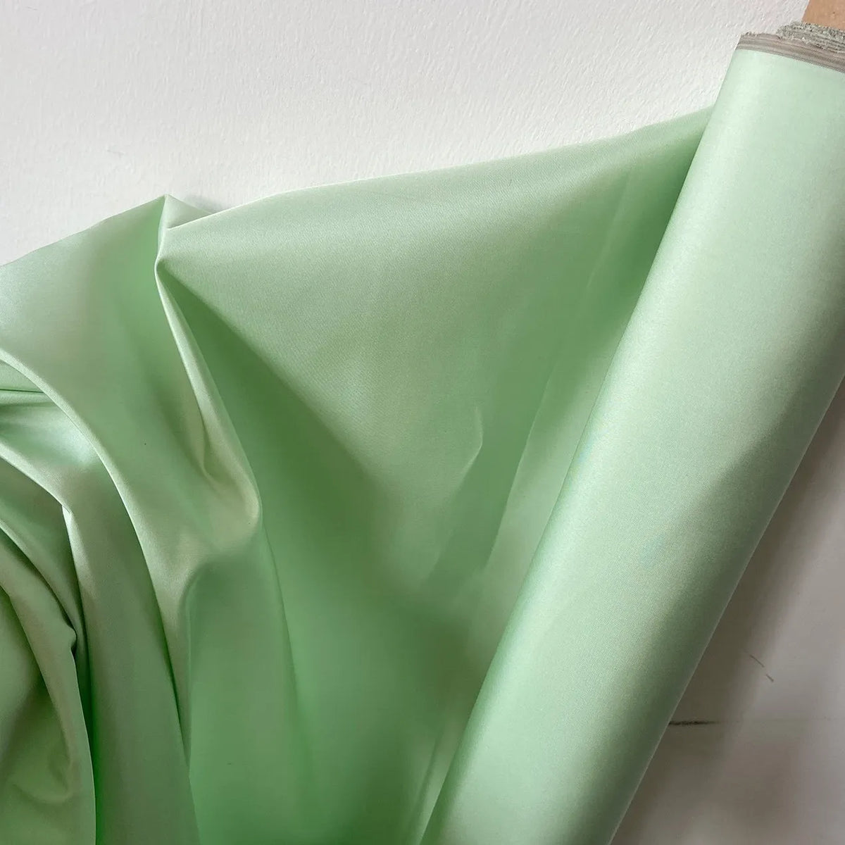 A bolt of Longan Craft Plain Color Taffeta Silk Fabric by the yard is displayed against a white background, highlighting its high-quality, smooth mulberry silk—ideal for bridal wear and special occasion garments.