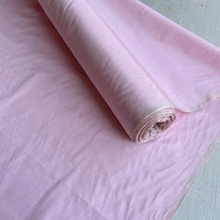 A roll of Longan Craft's Plain Color Taffeta Silk Fabric By The Yard, made from stiff 100 Mulberry silk, is unrolled to reveal its smooth, slightly shiny texture—perfect for high-quality bridal and evening gowns.