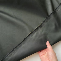 A hand holds the edge of Longan Craft’s Plain Color Taffeta Silk Fabric—stiff 100% Mulberry silk with raw, unfinished edges—ideal for crafting high-quality bridal gowns or elegant evening wear by the yard.