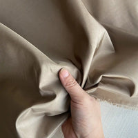 A hand pinches Plain Color Taffeta Silk Fabric by Longan Craft, showcasing its smooth, slightly reflective 100% mulberry silk—ideal for high-quality bridal and evening gowns.