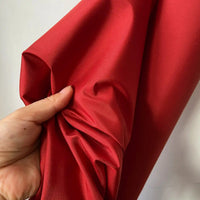 A hand gently gathers Longan Craft’s Plain Color Taffeta Silk Fabric by the yard—100% mulberry silk with a smooth, stiff texture—perfect for bridal or evening gowns, shown against a plain light background.