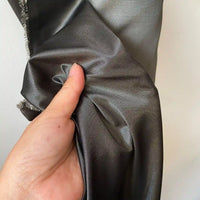 A hand holds and scrunches Plain Color Taffeta Silk Fabric by Longan Craft, a high quality, stiff 100% mulberry silk bridal fabric, against a light background.
