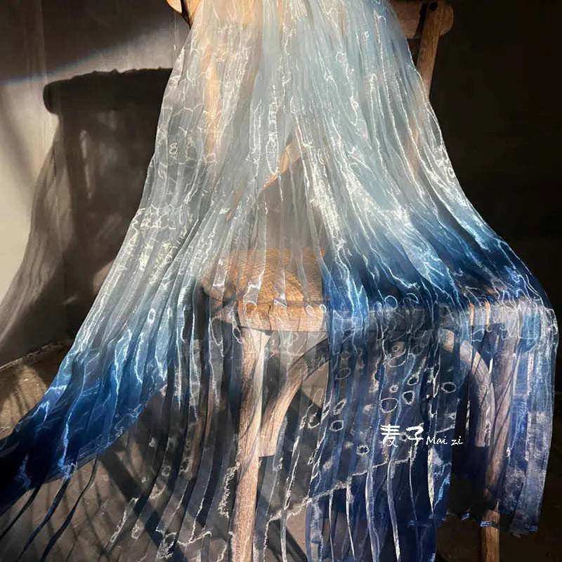 Longan Craft's Gradient Pleated Organza Fabric by the Yard features a shiny finish and a light blue-to-navy gradient, draping elegantly in sunlight—perfect for creating sophisticated wedding gowns.