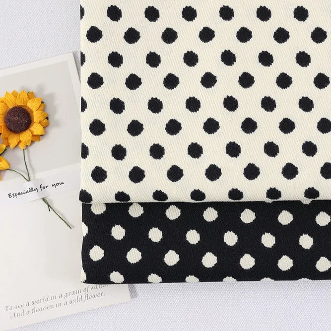 Two pieces of Longan Craft’s Polka Dot Print Corduroy Fabric By The Yard, featuring fine wale retro corduroy in black with white dots and white with black dots, are displayed beside a card adorned with two yellow artificial sunflowers and a handwritten note.