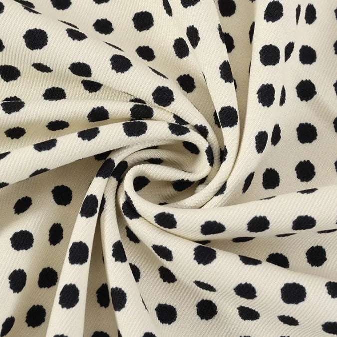 A detailed close-up of Longan Craft’s Polka Dot Print Corduroy Fabric By The Yard showcases its cream-colored, fine wale corduroy material twisted into a spiral at the center. The raised dotted pattern and soft texture of this retro corduroy apparel textile are clearly visible.