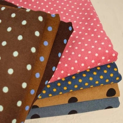 A stack of five folded pieces of Polka Dot Printed 21 Wales Corduroy Fabric, each featuring a different color and polka dot pattern.