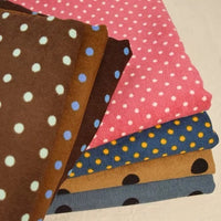 A stack of five folded pieces of Polka Dot Printed 21 Wales Corduroy Fabric, each featuring a different color and polka dot pattern.