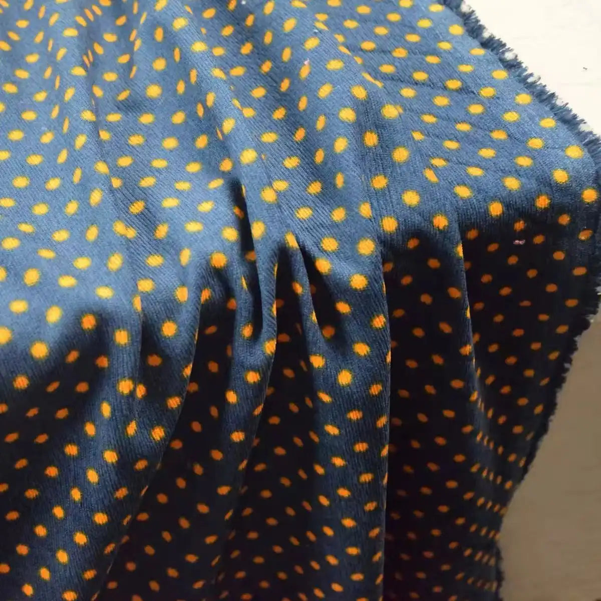 Longan Craft Polka Dot Printed 21 Wales Corduroy Fabric By The Yard in blue with an orange polka dot pattern, draped to reveal its fine wale texture.