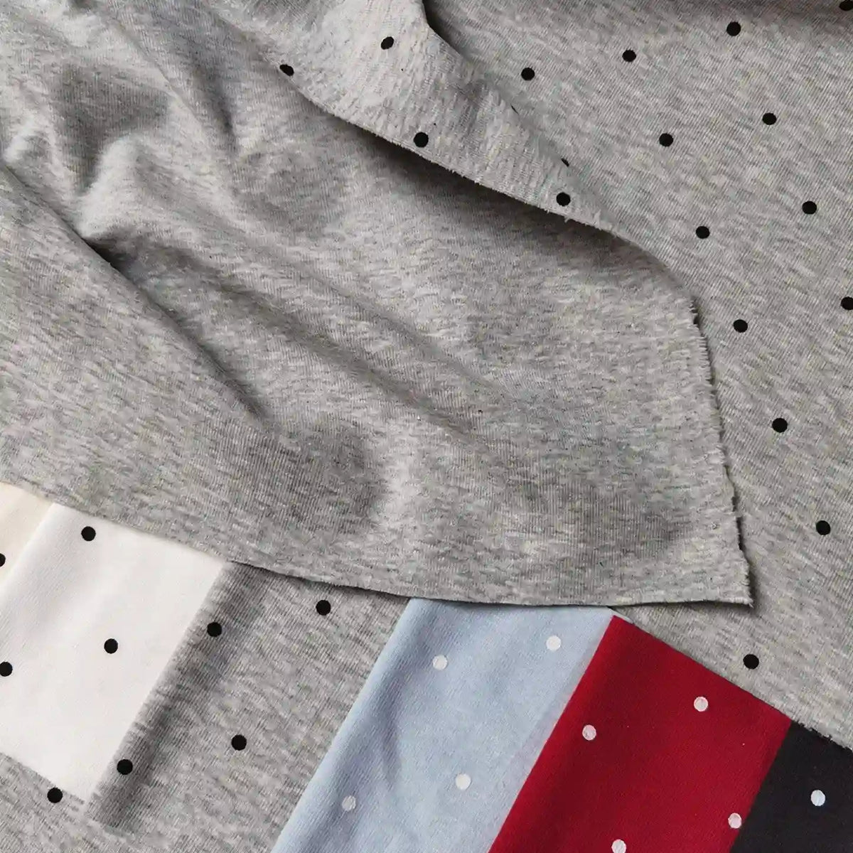 Folded pieces of multi-colored Polka Dot Printed Cotton 1*1 Rib Knit Fabric By The Yard featuring a ribbed texture and small polka dot prints.