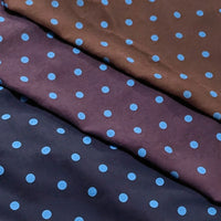 Three swatches of Polka Dot Printed Faux Suede Fabric By The Yard stacked diagonally, each in a different dark color with a pattern of light blue polka dots.