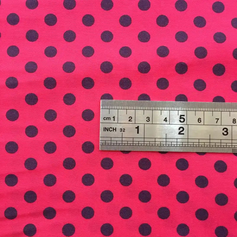 A metal ruler lies on Longan Craft’s Polka Dot Printed Peachskin Fabric By The Yard, a colorful microfiber polyester with black dots. The ruler shows measurements in centimeters and inches, the largest visible being 6 cm.