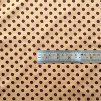 A silver ruler rests on Longan Craft's Polka Dot Printed Peachskin Fabric, a soft microfiber polyester with evenly spaced brown dots—highlighting the scale for choosing this DIY skirt material by the yard. Ruler shows both cm and inch measurements.
