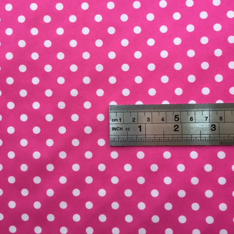 A metal ruler on Longan Craft Polka Dot Printed Peachskin Fabric shows the size of evenly spaced white dots. This colorful microfiber polyester material is perfect for DIY skirts and helps you visualize dot size for dressmaking projects.