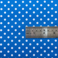 A metal ruler with inch and centimeter marks is placed on Longan Craft's Polka Dot Printed Peachskin Fabric By The Yard, a blue microfiber polyester fabric with white polka dots and a soft texture for DIY skirts.