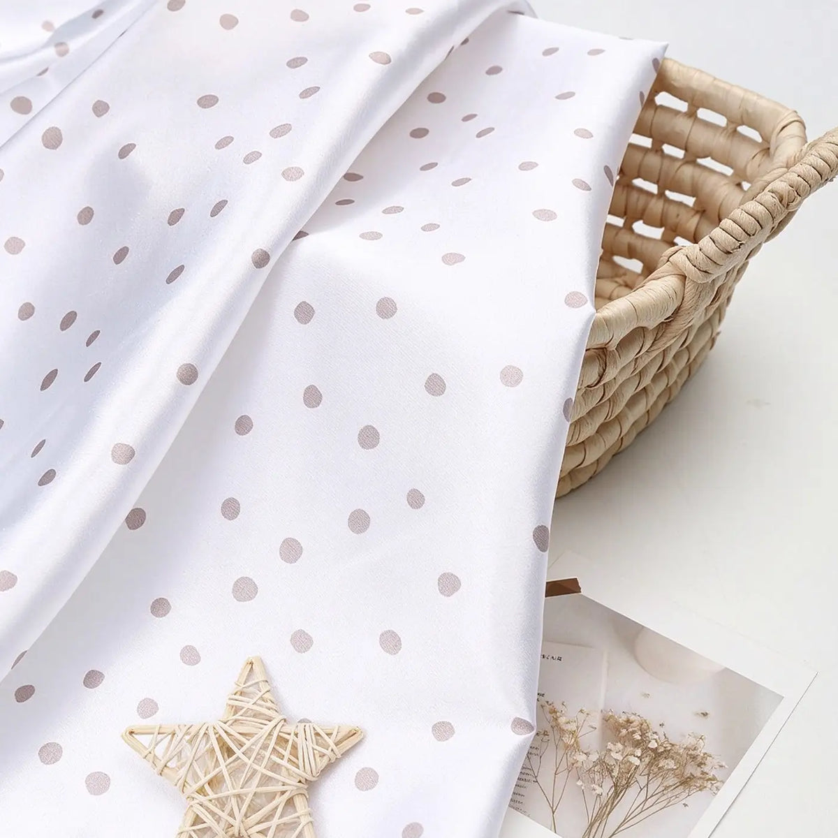 Polka Dot Printed Satin Fabric By The Yard in white draped over a woven basket.