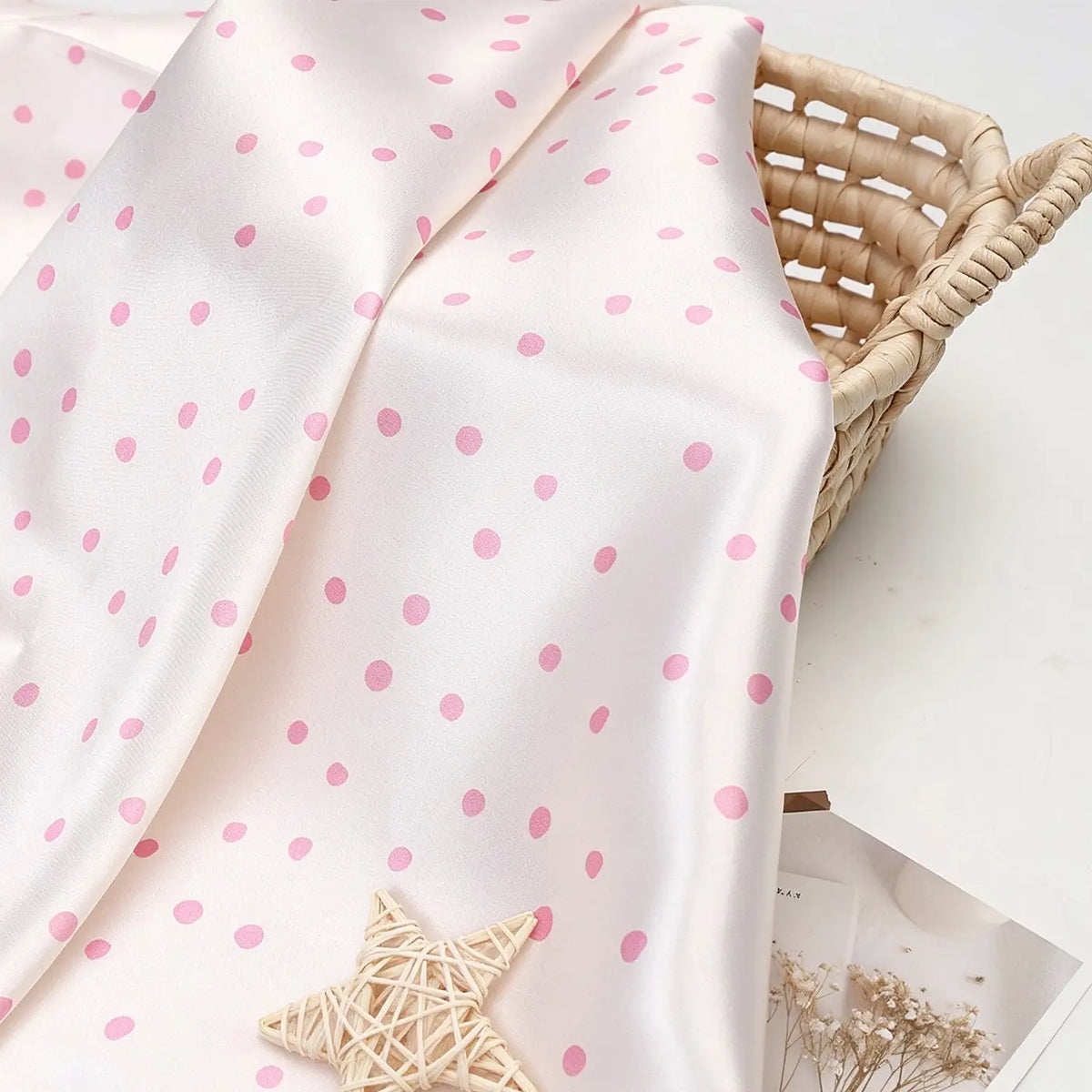 Polka Dot Printed Satin Fabric By The Yard in a cream-colored polka dot pattern draped over a woven basket.