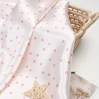 Polka Dot Printed Satin Fabric By The Yard in a cream-colored polka dot pattern draped over a woven basket.