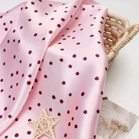 Light pink polka dot Polka Dot Printed Satin Fabric By The Yard draped over a wicker basket.