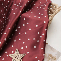 Maroon polka dot satin fabric from Longan Craft draped over a wicker basket.