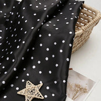 Black polka dot Polka Dot Printed Satin Fabric By The Yard draped over a wicker basket.