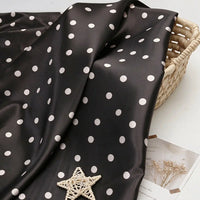 Polka Dot Printed Satin Fabric By The Yard draped over a woven basket.