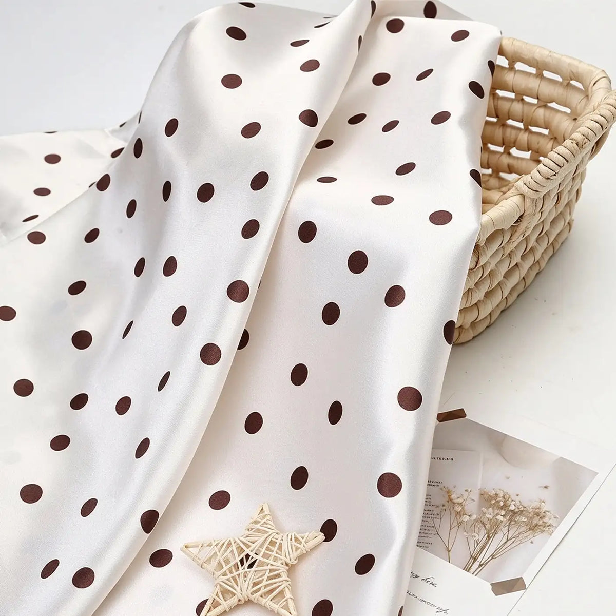 Polka Dot Printed Satin Fabric By The Yard in white draped over a woven basket.