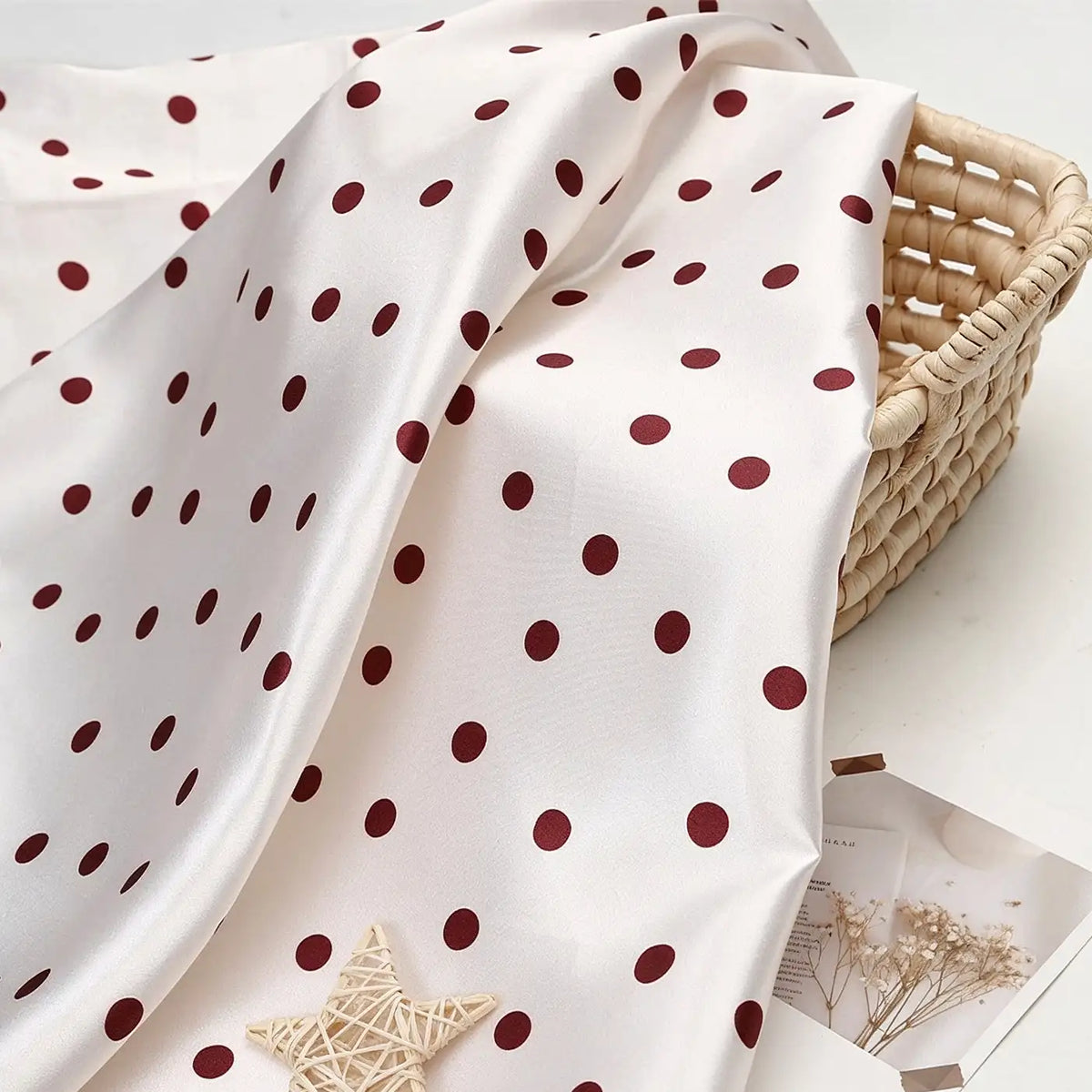 Polka Dot Printed Satin Fabric By The Yard in white draped over a woven basket.