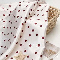 Polka Dot Printed Satin Fabric By The Yard in white draped over a woven basket.