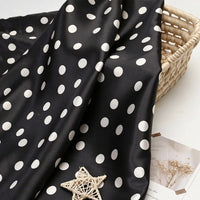 Polka Dot Printed Satin Fabric By The Yard draped over a woven basket.