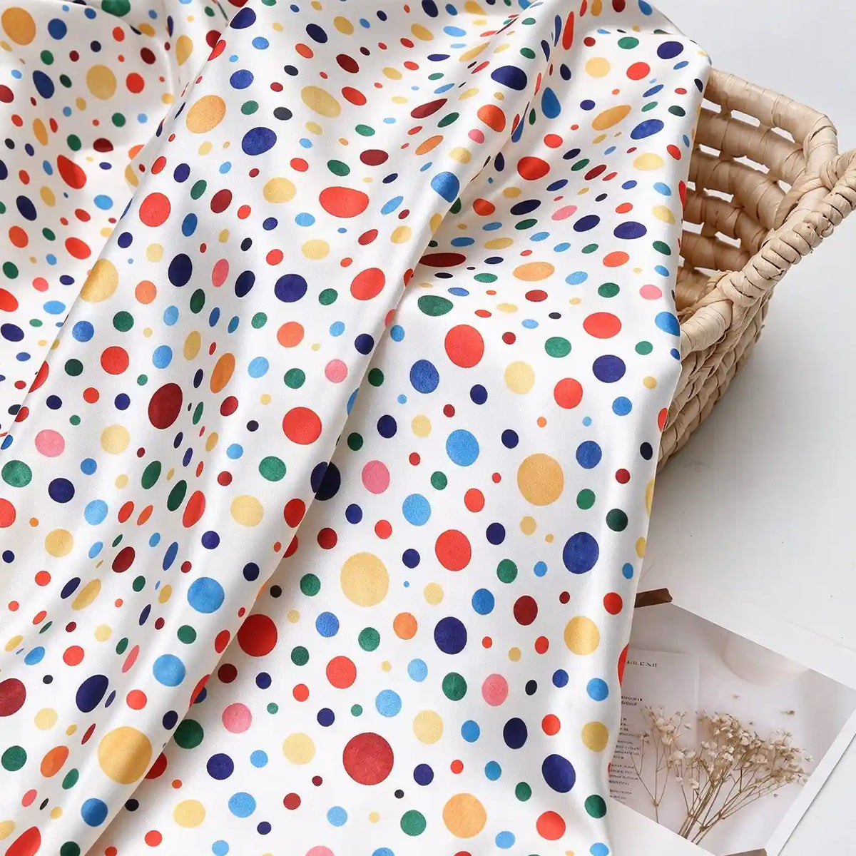 Polka Dot Printed Satin Fabric By The Yard in white draped over a woven basket.