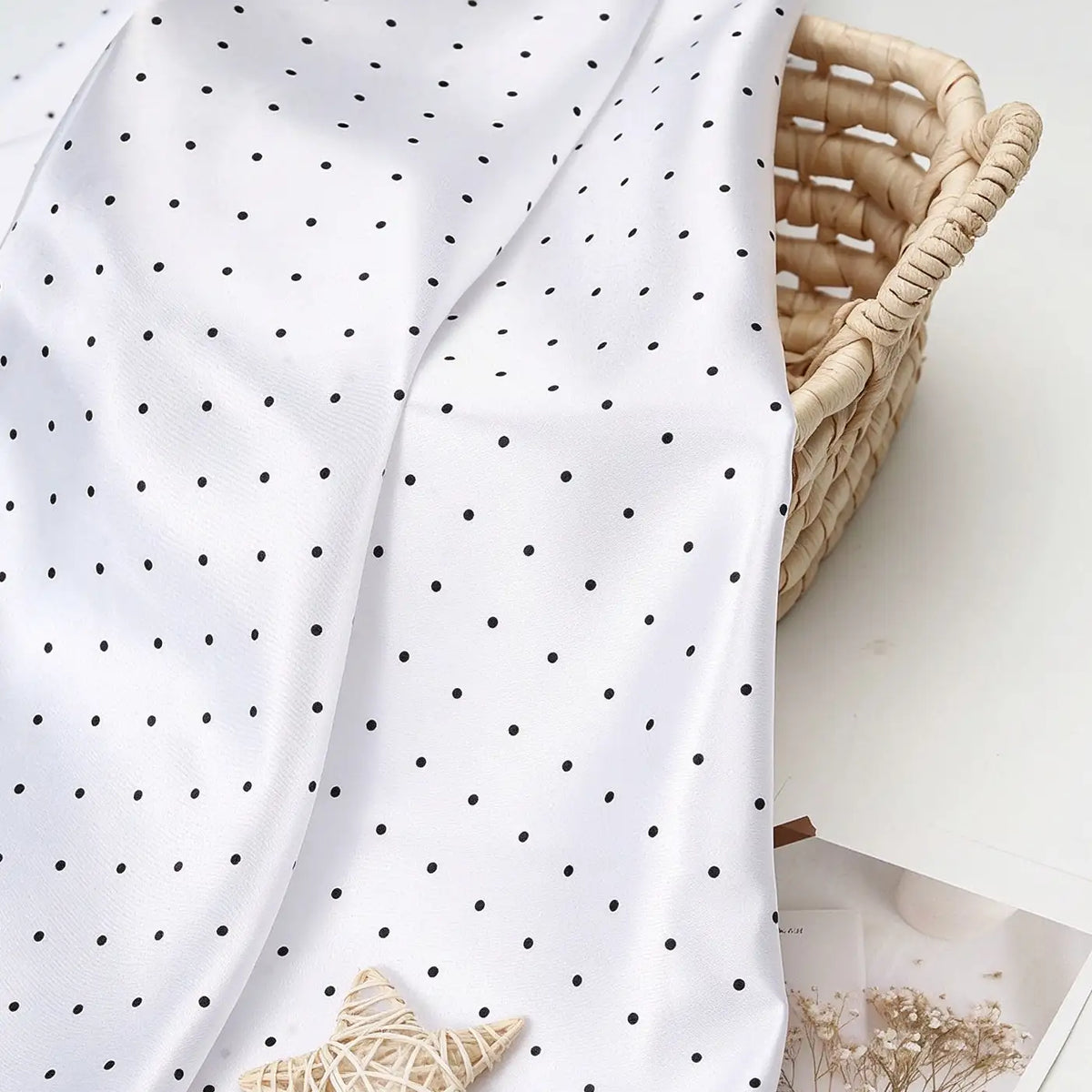 Polka Dot Printed Satin Fabric By The Yard draped over a woven basket.