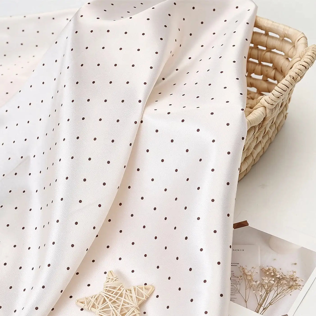 Polka Dot Printed Satin Fabric By The Yard in white draped over a wicker basket.