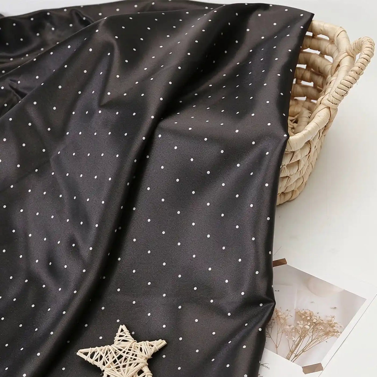 Black polka dot satin fabric from Longan Craft draped over a wicker basket.