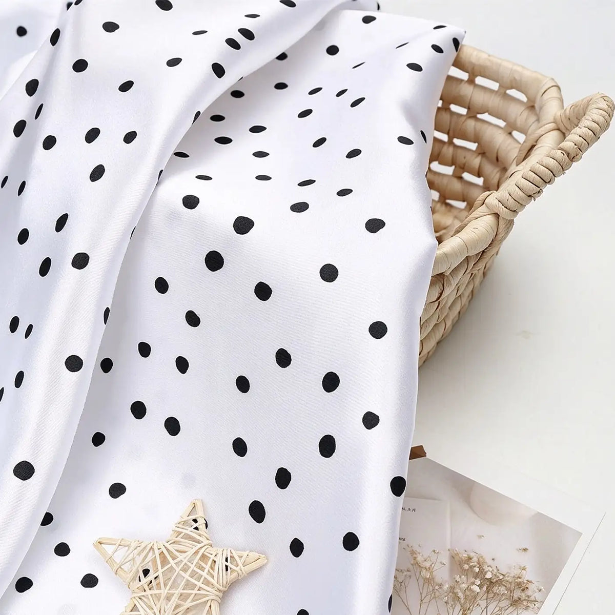 Polka Dot Printed Satin Fabric By The Yard draped over a woven basket, with a star-shaped ornament in the foreground.