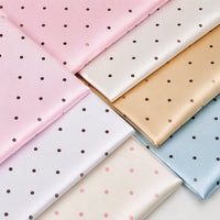 Folded squares of Polka Dot Printed Satin Fabric By The Yard in pink, white, gold, and light blue, each showcasing a repeating polka dot pattern.