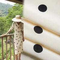 A person in a white dress with black polka dots made from Longan Craft’s Polka Dot and Floral Printed Viscose Fabric By The Yard stands on a balcony; next to them is a close-up of this fashionable 100% viscose material for long skirts.