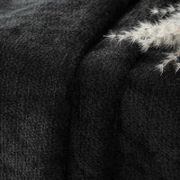 Close-up of Longan Craft Poly Chenille Fabric By The Yard, a solid color soft chenille upholstery material, showing its dark, textured, plush surface with small white feathery decor in the upper right corner.