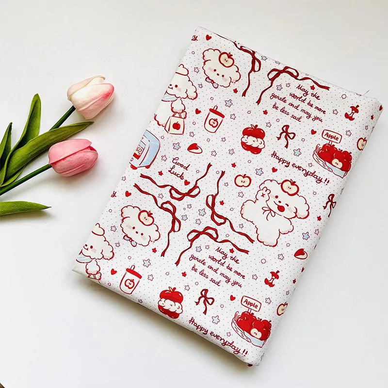 Puppy Apple Print Canvas Fabric By The Yard featuring a red line-art pattern of puppies, apples, and phrases like Happy everyday!! and May the world be more gentle, positioned next to two pink tulips.