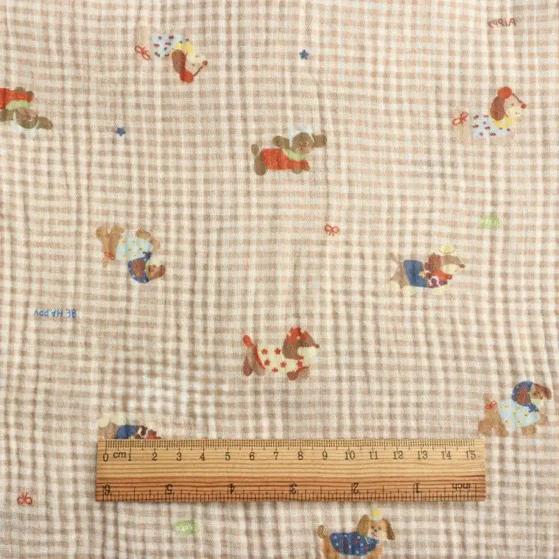 A wooden ruler in centimeters rests on Longan Craft’s Puppy Print Gingham Double Gauze Fabric—brown plaid, pure cotton with playful puppy prints. The breathable, crinkled gauze is ideal for sleepwear and sold by the yard.