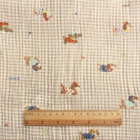 A wooden ruler in centimeters rests on Longan Craft’s Puppy Print Gingham Double Gauze Fabric—brown plaid, pure cotton with playful puppy prints. The breathable, crinkled gauze is ideal for sleepwear and sold by the yard.