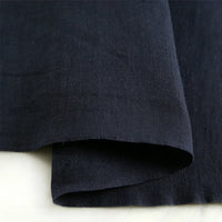 A close-up of Longan Craft’s Pure Color 100 Linen Fabric By The Yard in dark navy blue, highlighting its rich texture and natural folds on a light surface—a comfy, medium-weight linen ideal for casual wear.