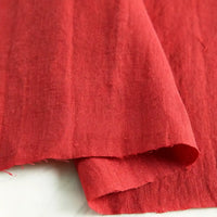 A close-up of Longan Craft’s Pure Color 100 Linen Fabric by the yard in a solid red shade, draped on a white surface to showcase its medium weight texture and natural weave—ideal for comfortable casual wear.
