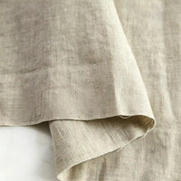 A close-up of Longan Craft’s Pure Color 100 Linen Fabric By The Yard in natural beige, folded to showcase its medium weight, visible texture, and weave details—ideal for comfy casual wear.